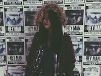 a woman standing in front of a wall of posters